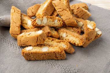 Gri peçeteli Biscotti di prato. Bir yığın geleneksel İtalyan cantuccini fındık kurabiyesi. Hasır sepette bademli ev yapımı cantucci kurabiyesi.
