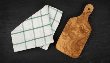 Kırsal bir peçeteyle zeytin ağacı kesme tahtası. Üst görünümü kopyalayan tahta arkaplanı kesiliyor