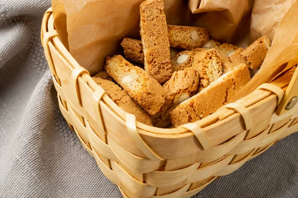 Biscotti di prato 'nun rustik masa örtüsü çuval bezi arka planı. Geleneksel İtalyan fındık kurabiyeleri. Hasır sepette bademli ev yapımı cantucci kurabiyesi.