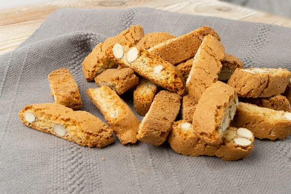 Gri peçeteli Biscotti di prato. Bir yığın geleneksel İtalyan cantuccini fındık kurabiyesi. Hasır sepette bademli ev yapımı cantucci kurabiyesi.