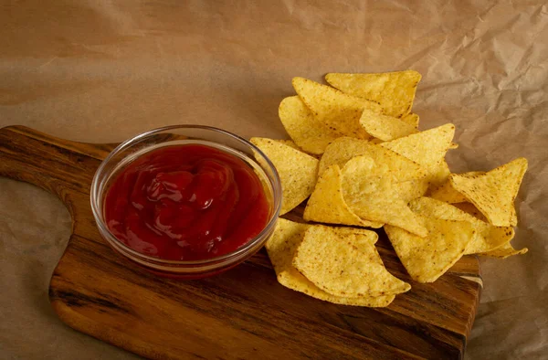 Kırsal arka planda kırmızı soslu üçgen mısır cipsi. Nacho tortilla için Meksika cipsi, mısır cipsi, mısır cipsi veya buruşuk kağıt üzerinde salsa soslu totopos.