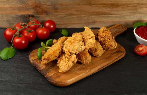 Breaded Fried Chicken Wings, Fingers and Drumsticks on Wooden Rustic Background. Hot Crispy Chicken Nuggets, Fillet Strips, Meat Pieces in Breadcrumbs