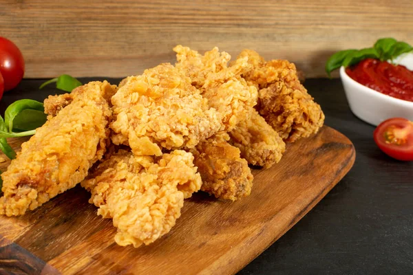 Breaded Fried Chicken Wings, Fingers and Drumsticks on Wooden Rustic Background. Hot Crispy Chicken Nuggets, Fillet Strips, Meat Pieces in Breadcrumbs