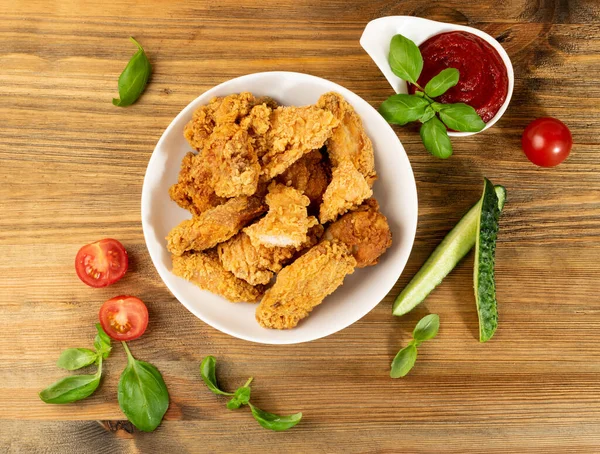 Breaded Fried Chicken Wings, Fingers and Drumsticks on Wooden Rustic Background Top View. Hot Crispy Chicken Nuggets, Fillet Strips, Meat Pieces in Breadcrumbs