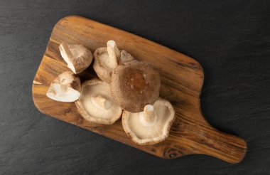 Tahta kesim tahtasında taze şitake mantarı yığını. Çiğ bok, sağlıklı organik Asya mantarı.