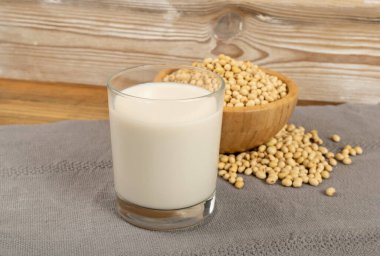 Bardakta soya sütü ve tahta kasede soya fasulyesi. Köy arka planında taze soya sütü