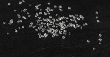 Siyah arka planda büyük şeker kristalleri yakın plan. Sukroz kristalleri, deniz tuzu kayaları ya da seçici bir odak noktası olan yiyecek üzerine sodyum tuz dokusu.