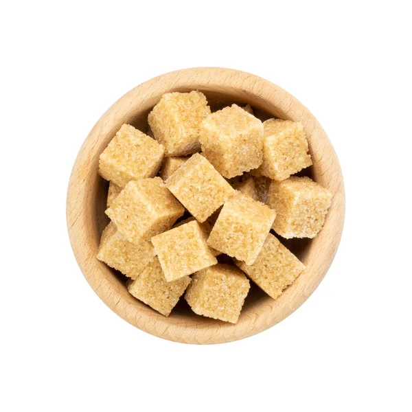 Beyaz zemin üzerinde izole şeker küpleri. Tahta kasede işlenmemiş kahverengi şeker, tatlandırıcı, glikoz üst görünüm.