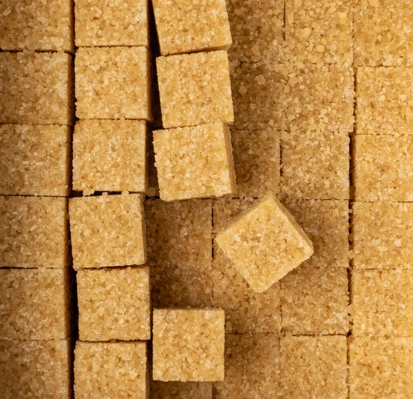 Raw brown sugar cubes isolated on white background. Unrefined cane sugar square pixels texture pattern top view