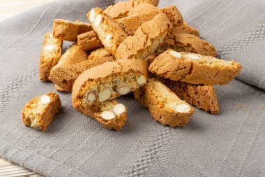 Gri peçeteli Biscotti di prato. Bir yığın geleneksel İtalyan cantuccini fındık kurabiyesi. Hasır sepette bademli ev yapımı cantucci kurabiyesi.
