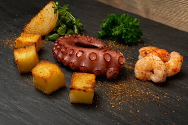 Traditional greek grilled seafood on a black stone plate served with shrimps and vegetables. Delicious barbecue octopus tentacle with fresh greens and spices clipart