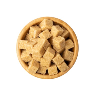 Beyaz arka planda izole edilmiş kahverengi şeker küpleri yığını. Tahta kasenin üst manzarasında işlenmemiş kamış şekeri