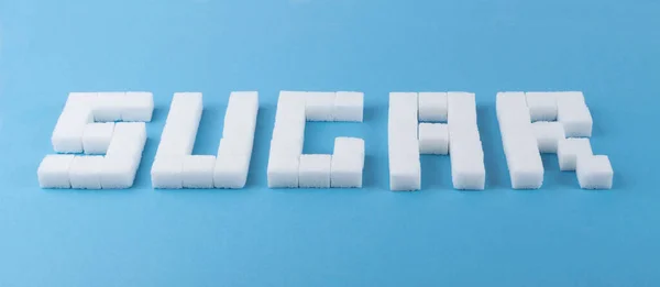 Socker Ord Vitt Socker Kuber Blå Bakgrund Oraffinerade Rörsockerbitar — Stockfoto