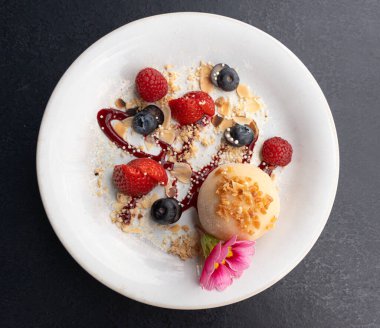 Meyveli mochi pirinç keki, beyaz daifuku, Japon geleneksel tatlısı, kremalı ve anko dolgulu yuvarlak wagashi, çilekli Asya şekeri, yaban mersini ve siyah arka planda çiçek.