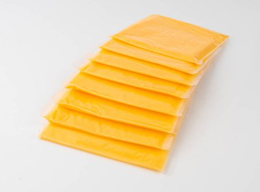 Amerikan peyniri izole edilmiş, işlenmiş peynir dilimi, ince sarı çedar peyniri, beyaz arka planda tost ve sandviç için plastik bir pakete sarılmış.