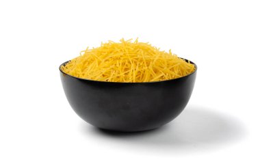 Çiğ vermicelli izole edilmiş, altın çorbalı makarna, küçük ev yapımı erişte, ince makarna, beyaz arka planda siyah kasede İtalyan filini makarna.