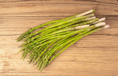 Ahşap Rustik Masaüstü 'nde bir demet Raw Garden kuşkonmazı. Taze Yeşil Bahar Sebzeleri, Yenilebilir Kuşkonmaz Resmi Yaylar Üst Kapak Kapağı