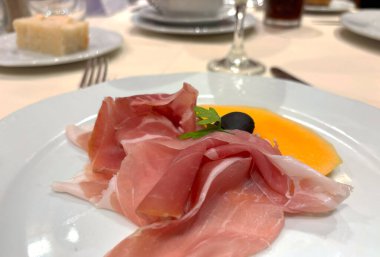 Prosciutto dilimleri beyaz tabakta. İspanyol jamonu, restoranda kavun, makro fotograf parma jambonu, Serrano ya da Iberico yakın plan bulanık.