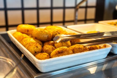 Otel büfesinde derilerinin içinde pişmiş patatesler. Her şeyi kapsayan öğle yemeği, kızarmış soyulmamış patates makro fotoğraf bulanık arka planda.