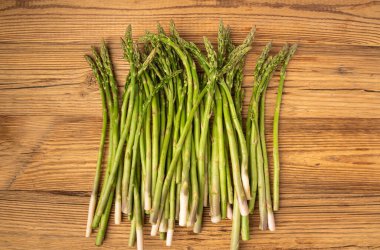 Ahşap Rustik Masaüstü 'nde bir demet Raw Garden kuşkonmazı. Taze Yeşil Bahar Sebzeleri, Yenilebilir Kuşkonmaz Resmi Yaylar Üst Kapak Kapağı