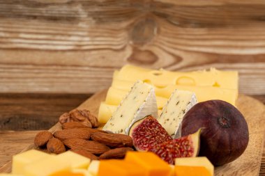 Peynir tabağı çeşitliliği, sarı, beyaz ve mavi gorgonzola tabağı, Munster, dört peynirli pano, çeşitli doğranmış süt ürünleri, ahşap üzerinde kokulu Fransız peyniri.