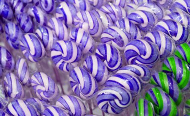 Renkli lolipop dokusu, çubukta sarmal şeker, renkli çizgili lolipop, yuvarlak meyve karamelli, çok renkli şekerleme, daire şeklinde lolipop yakın plan, seçici odak ve bulanık arkaplan