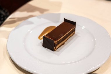 Restoran tabağındaki yatağa benzeyen bir parça çikolatalı pasta. Tuhaf yemekler, bulanık odak.