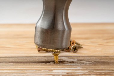 Çekiç vidaya çarpıyor. Hızlı ama verimsiz bir çözüm. Altın vidalar kapanıyor, endüstri donanım makro dokusu