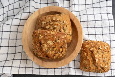 Balkabağı tohumlu ekmek, pepita tohumlu üç rulo kahvaltı. Fitness Square Bun, sağlıklı burger, kabak tohumlu çörek kırsal masa örtüsü arkaplan manzarası