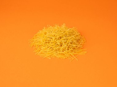 Turuncu arka planda çiğ vermicelli, yuvarlak altın çorba makarna, küçük ev yapımı erişte, ince makarna, İtalyan sarısı filini makarna.