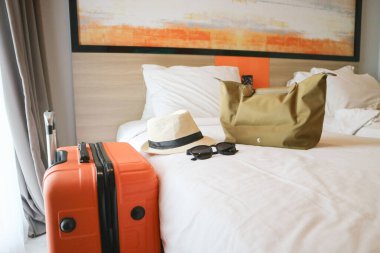 Yatağın yanında bavul ve sırt çantalı bir otel odası.