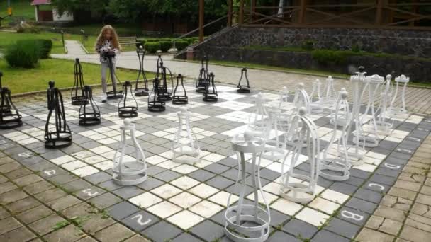La ragazza muove pezzi giganti di scacchi. Attività all'aperto — Video Stock