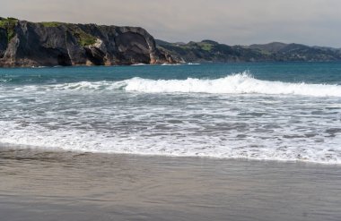 Soğuk Atlantik Okyanusu, dalgaların beyaz köpüğü ve Zumaia sahilinin altın kumu. Kuzey İspanya 'nın sert havası