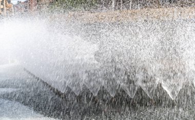 Çeşme suyu sıçraması, şelale şelalesi yazı dokulu arka plan. Şehir yaz parkı çeşmesi, akan su akıntısı bulanık arkaplanı kapatıyor