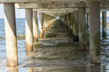 Concrete pier piles receding into perspective over water. View from below on thick vertical supports submerged in sea or lake, with strong geometric lines