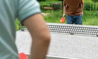 Parkta masa tenisi. Masa tenisi yaz sporu, baba ve oğul masa tenisi, seçici odaklı, bulanık arka plan.