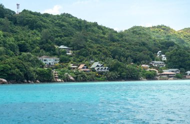 Seaside villas and tropical greenery on Praslin Island coastline seen from the ferry to La Digue in Seychelles