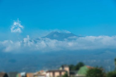 Etna Dağı belirgin bir volkanik formla Sicilya siluetine hükmediyor. Aşağıdaki vadinin zirvesinden duman yavaşça yükseliyor.