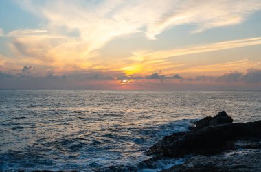 Sicilya 'da kayalık sahil kenarında gün batımı ya da gün doğumu. Altın ışık su yüzeyine yansıyor yumuşak dalgalar ve köpükle