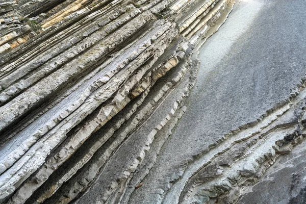 Katmanlı kayalar, sinek dokusu arka planı. Tortul kaya, çizgiler taş desen, başkalaşım bayrağı, doğa taşı duvar yapısı, eski kaba mineral oluşumu.