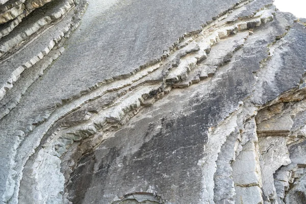 Katmanlı kayalar, sinek dokusu arka planı. Tortul kaya, çizgiler taş desen, başkalaşım bayrağı, doğa taşı duvar yapısı, eski kaba mineral oluşumu.