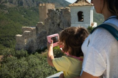 Çocuk, güneşli bir günde ebeveyninin eşliğinde tarihi yerleri keşfeder, oyuncak kamerayla anıları yakalar.