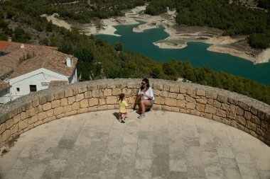 Anne ve kızı özel bir anı paylaşırken taş duvar manzaralı bir gölün nefes kesici manzarasının tadını çıkarıyorlar.