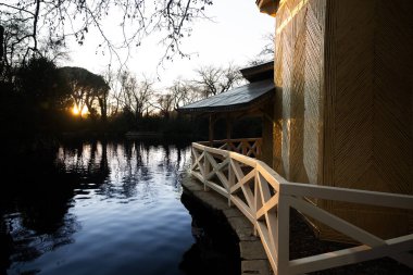 Kristal sarayın manzarası Emeklilik Parkı, Madrid, İspanya 'da sonbaharda gün batımında sakin gölü yansıtıyor.