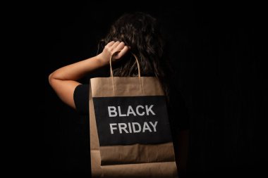 Elinde siyah cuma tabelası olan alışveriş çantası tutan kadın mevsimlik indirimleri ve alışveriş anlaşmalarını destekliyor.