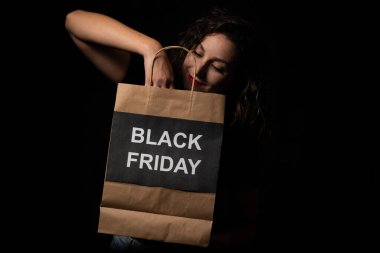 Kara Cuma alışveriş çantası tutan mutlu kadın, büyük indirimlerden ve satışlardan zevk alıyor.