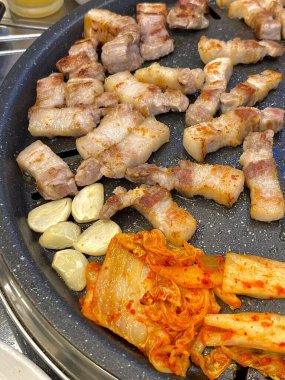 Sulu ızgara samgyeopsal baharatlı, keskin kimchi ile eşleştirilmiş, her cızırtılı, ağız sulandıran ısırıkta zengin, lezzetli etten ve fermente edilmiş cesur bir armoni sunuyor..