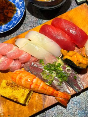 Çeşitli malzemeler ve canlı renklerle sanatsal olarak düzenlenmiş taze suşi çeşitleri. Bu geleneksel Japon yemeği bir deneyim için sirkeli pirinç, deniz ürünleri ve sebzeleri birleştirir..