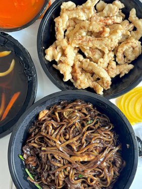 Zengin siyah fasulye sosuna bulanmış kalın, çiğnenmiş erişteli klasik Kore-Çin karışımı, yanında gevrek tangsuyuk, bol yağda kızartılmış domuz eti ve tatlı ve ekşi sos servis edilir..