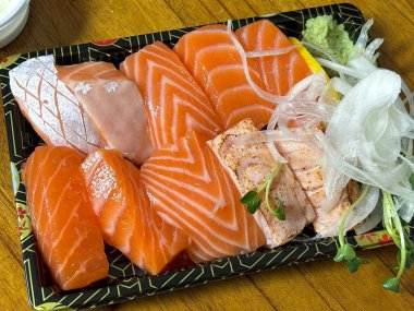 Çeşitli malzemeler ve canlı renklerle sanatsal olarak düzenlenmiş taze suşi çeşitleri. Bu geleneksel Japon yemeği bir deneyim için sirkeli pirinç, deniz ürünleri ve sebzeleri birleştirir..